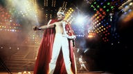 Freddie Mercury mit Krone und rotem Samtmantel bei einem Auftritt in Mannheim 1986