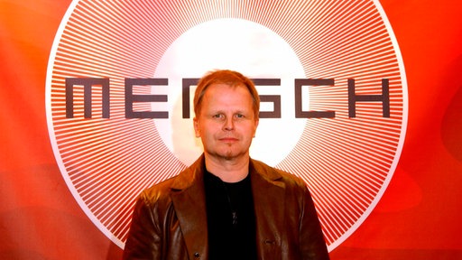 Hebert Grönemeyer vor dem Logo seines Albums "Mensch" (2002)