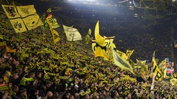 Die Fans auf der Dortmunder Südtribüne halten ihre Schals in die Höhe und singen