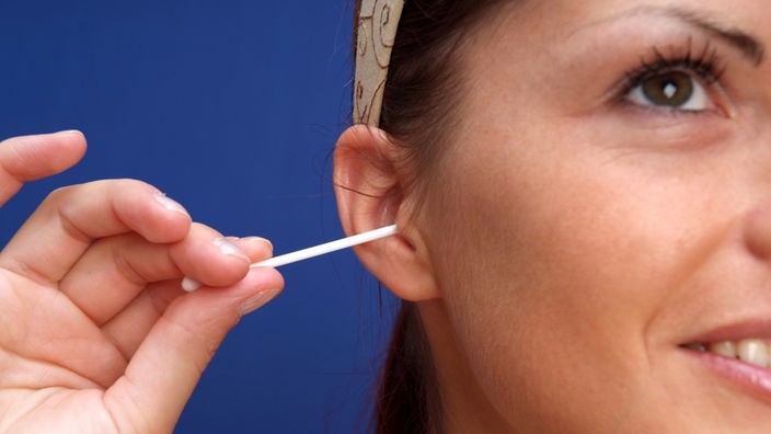 Frau reinigt Ohren mit Wattestäbchen