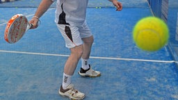 Ein Mann spielt in einer Halle Padel