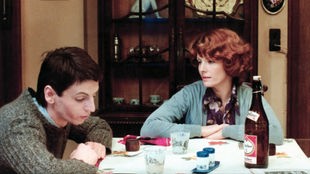 Szene aus dem belgisch-französischen Spielfilm "Jeanne Dielman" (1975): Sylvain Dielman (Jan Decorte) und Jeanne Dielman (Delphine Seyrig) sitzen an einem Tisch und unterhalten sich