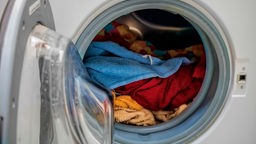 Bullauge einer Waschmaschine mit bunten Handtüchern