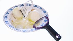 Zwiebeln liegen mit Sparschälern auf einem Teller