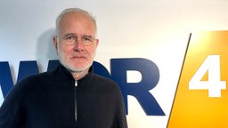 Harald Schmidt vor dem WDR 4-Logo