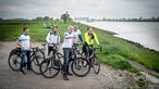 Probefahrt zur NRW Radtour 2023: Bastian Bender genießt gemeinsam mit vier weiteren Radfahrern die Aussicht auf den Rhein