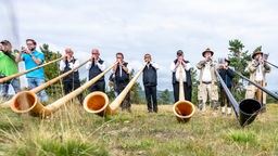 Alphornbläser spielen während der Messe auf dem Ettelsberg in Willingen ihr Instrument (2022)