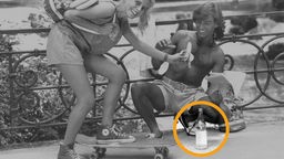 sommerliche Straßenszene aus den 80ern, in schwarzweiß: Eine Mineralwasserflasche steht auf dem Boden vor einer jungen Frau mit Skateboard und einem jungen Mann mit freiem Oberkörper, mit Zeitung in der Hand