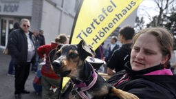 Ein Hund wartet mit seinem Frauchen vor der Ausgabestelle der Tiertafel in Köln-Höhenhaus