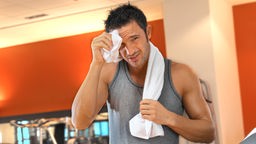 Ein Mann trocknet seine Stirn nach einem Workout im Gym ab