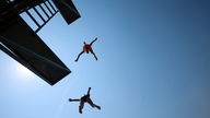 2 Jungen springen von einem Sprungbrett im Freibad