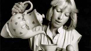 Junges Mädchen gießt aus einer Blümchenkanne Kaffee in eine Tasse, 1983