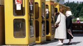 Sechs gelbe Telefonzellen der Deutschen Bundespost mit davor wartenden Kunden 1985