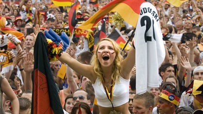 Deutsche Fußballfans mit Deutschlandfahnen jubeln auf der Fan-Meile Berlin anlässlich des Spiels Deutschland:Argentinien der FIFA Fussball Weltmeisterschaft 2006.
