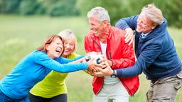 Eine Gruppe Senioren spielt mit einem Fußball im Park