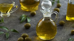 Hohe Ansicht auf eine Flaschen, gefüllt mit Olivenöl, auf einem Marmor Hintergrund. 