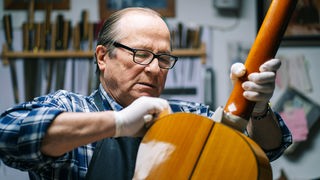 Senior-Handwerker mit Gitarre in einer Werkstatt
