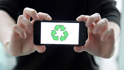 Ein Mann hält ein Smartphone mit einem Recycling-Symbol in der Hand