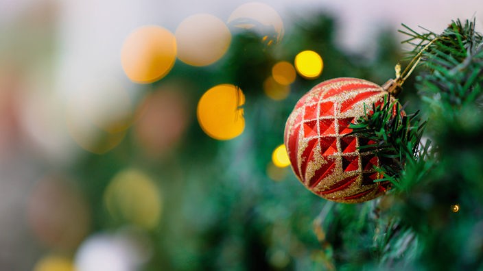 Christbaumkugel an einem festlich geschmückten Tannenbaum auf dem Weihnachtsmarkt