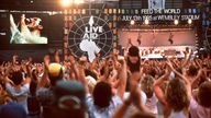 Bei einem Auftritt von Queen im Rahmen des Live-Aid-Festivals 1985 steht Freddie Mercury auf der Bühne, die Menge jubelt ihm zu