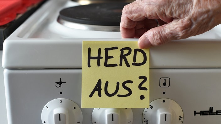 Ein Klebezettel mit dem Schriftzug «Herd aus?» klebt an einem Herd neben den Drehknöpfen. 