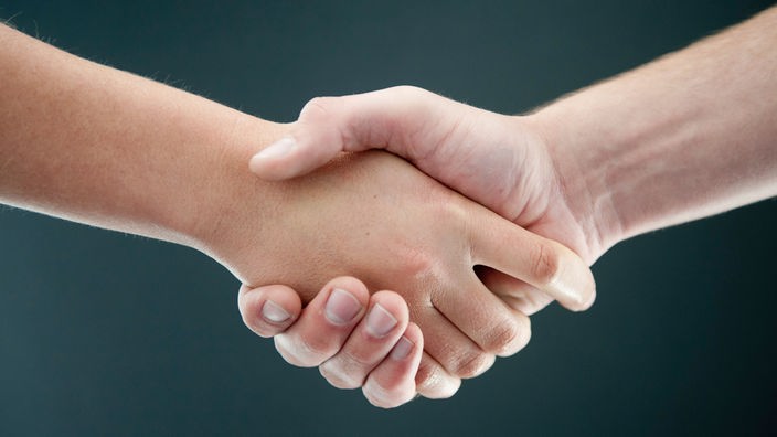 Zwei Menschen geben sich nach einem Streit die Hand.