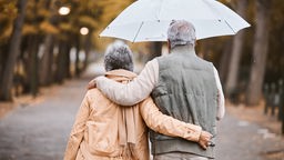 Zwei Senioren spazieren im Regen