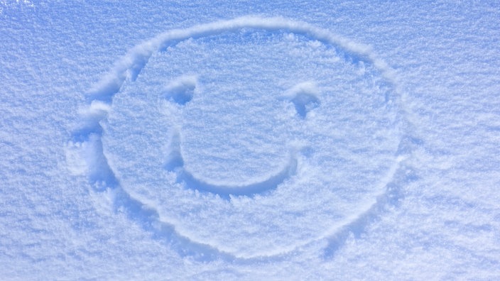 Freundliches Smiley-Gesicht in den Schnee gezeichnet 