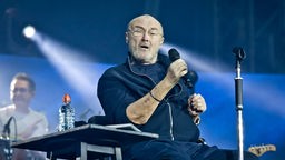 Phil Collins sitzend auf der Bühne im Berliner Olympiastadion 2019