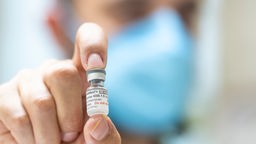 Ein Apotheker hält eine Ampulle mit 6 Dosen des neuen an die Omikron-Sublinie XBB.1.5 angepassten Corona-Impfstoffs in der Hand