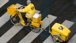 Ein Mitarbeiter der Deutschen Post fährt in Stuttgart (Baden-Württemberg) über einen Zebrastreifen