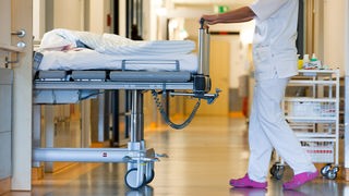  Eine Krankenschwester schiebt ein Bett über den Flur