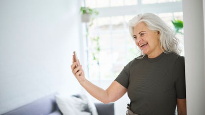 Frau mit grauen Haaren telefoniert mit dem Smartphone