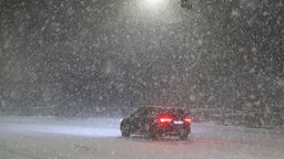 Ein Auto steht auf einer verschneiten Straße während eines Schneesturms