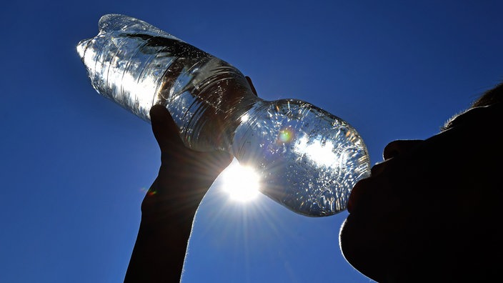 Junge trinkt Wasser aus einer Plastikflasche bei grosser Hitze