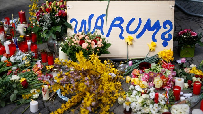 08.04.2018, Nordrhein-Westfalen, Münster: Ein Schild mit der Aufschrift "Warum?" liegt neben Blumen am Tatort der Amokfahrt von Münster.