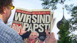 Ein Mann hälst die Titelseite mit der Schlagzeile "Wir sind Papst" der Bild-Zeitung in der Hand