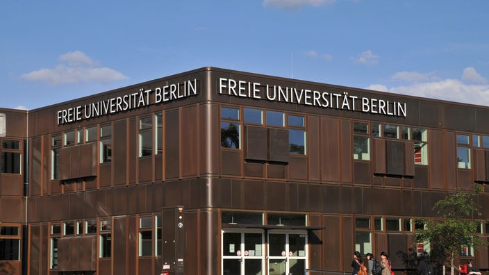 freie Universität Berlin, in rostbraunem Farbton, Hauptgebäude, davor gehen Menschen