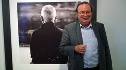 Lothar Schirmer steht vor einem Bild bei einer seiner Ausstellungen