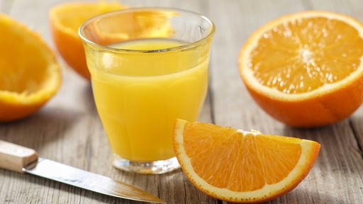 gepresster Orangensaft im Glas mit aufgeschnittenen Orangen