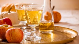 Cidre in zwei Gläsern, auf einem Tablett mit Äpfeln.