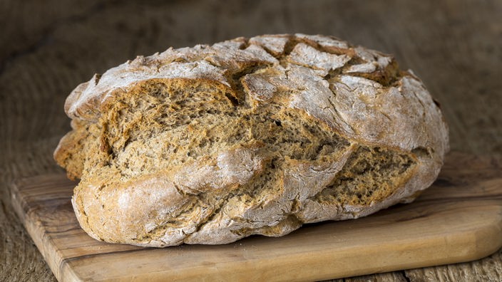 Ein Laib Brot auf einem Holzbrett, Symbolbild, kann von Rezeptdetails abweichen.