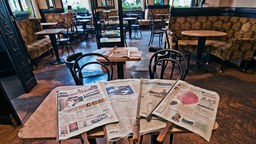 Im "Cafe Tirolerhof" liegen Tageszeitungen für die Gäste auf einem Tisch.