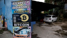 Ein Schild an einer Autowerkstatt weist auf Bitcoin als Zahlungsmöglichkeit hin
