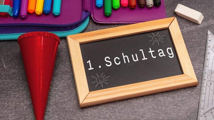 Schulsachen und eine kleine Kreidetafel mit der Aufschrift "1. Schultag"
