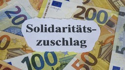 Zettel "Solidaritätszuschlag" liegt auf Geldscheinen