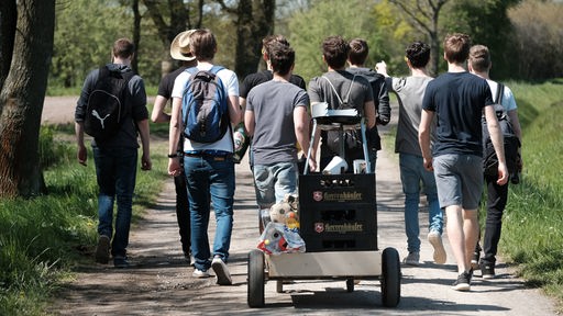 Eine Gruppe junger Männer mit einem mit Bier gefüllten Bollerwagen.