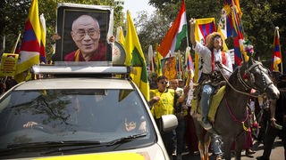 Exil-Tibeter in Indien demonstrieren anlässlich der Besetzung durch China vor 60 Jahren und tragen dabei neben Fahnen, auch ein Portrait des Dalai Lama mit sich.