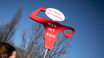 Auf einer Demonstration in Berlin zum Weltfrauentag ist ein Schild in Form einer Gebärmutter zu sehen. Darauf steht: "My body, my choice - weg mit §218!"