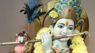 Das Bild zeigt die Darstellung des hinduistischen Gottes Krishna mit Flöte als Figur in einem Tempel.